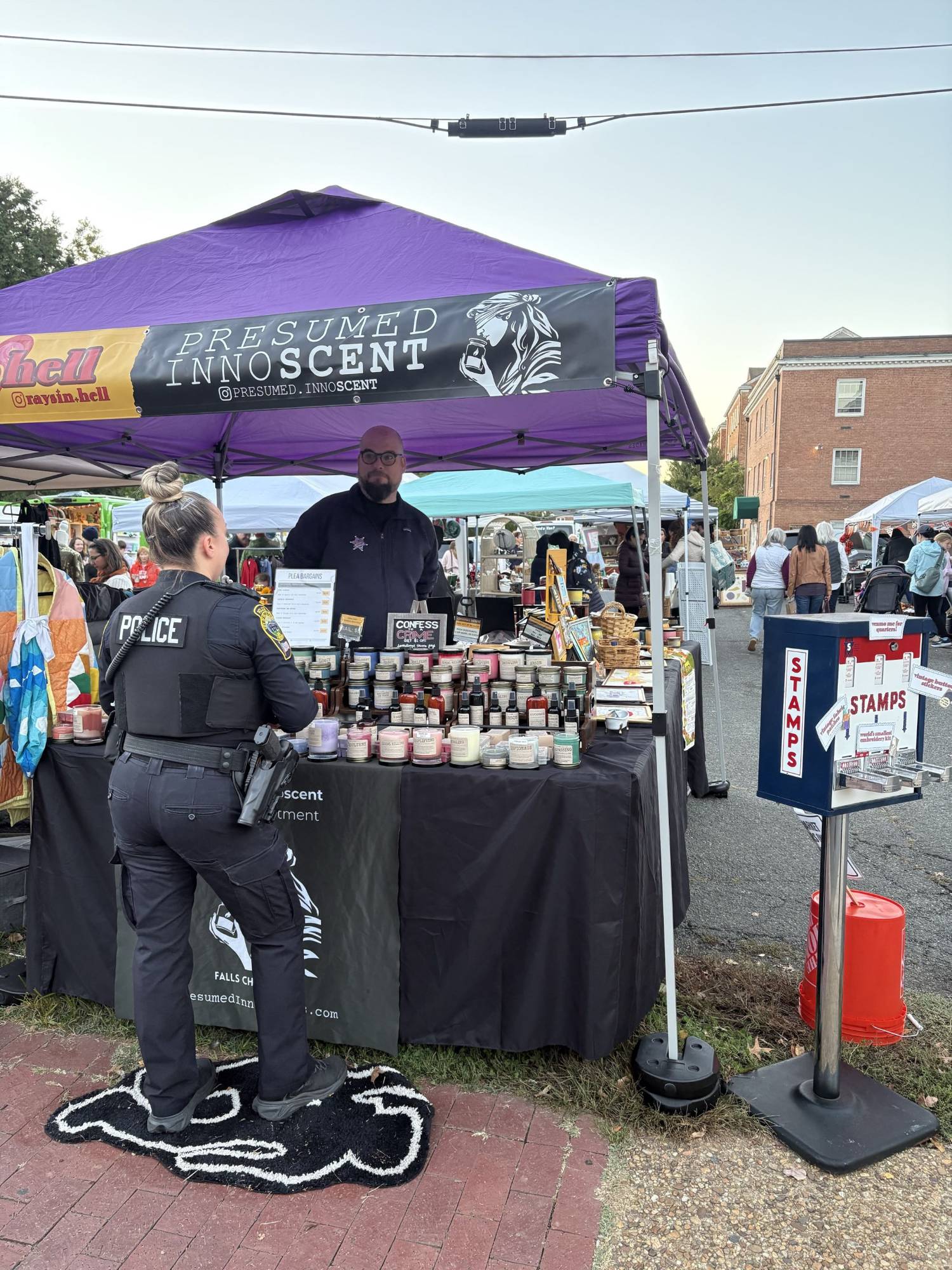 A Falls Church City police officer visits the Presumed Innoscent and Raysin' Hell booth at the Stylish Patina Fall Market